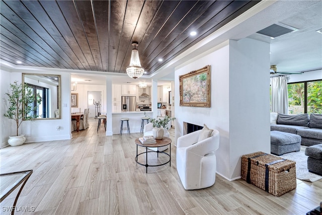 living room with a notable chandelier, wood ceiling, a fireplace, and light hardwood / wood-style flooring