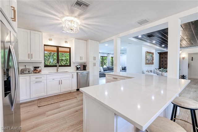 kitchen featuring white cabinets, appliances with stainless steel finishes, light wood-type flooring, and sink