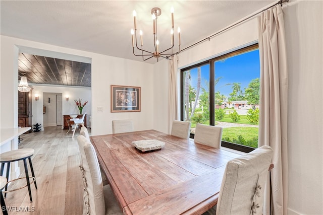 dining space with light wood-type flooring, an inviting chandelier, and plenty of natural light