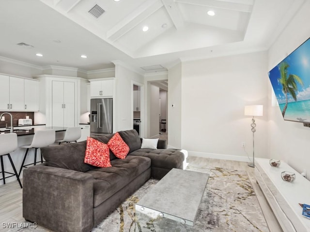 living room featuring lofted ceiling with beams, light wood-type flooring, and ornamental molding