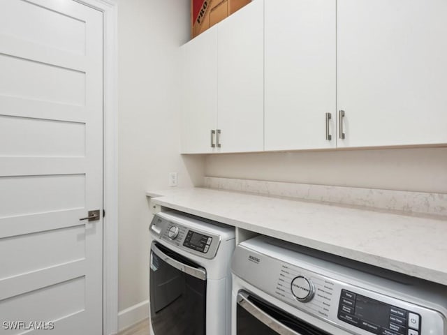 washroom with washing machine and clothes dryer and cabinets