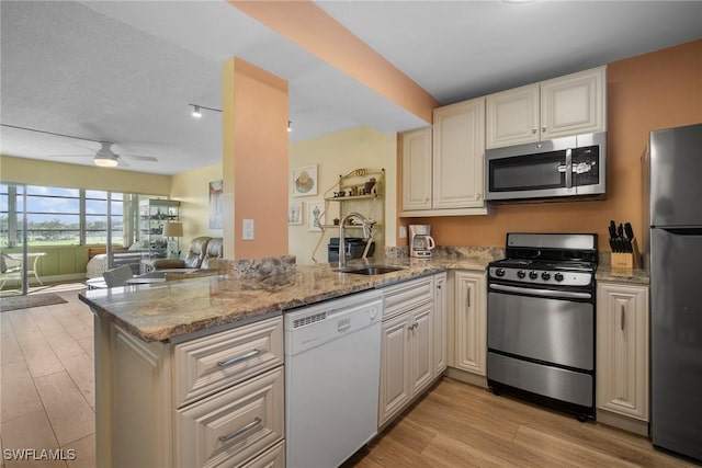 kitchen featuring sink, light stone counters, kitchen peninsula, and stainless steel appliances