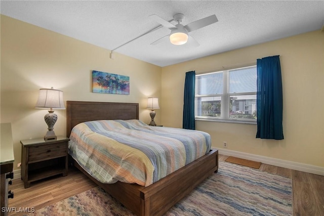 bedroom with a textured ceiling, hardwood / wood-style flooring, and ceiling fan