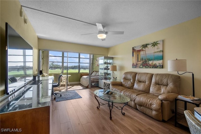 living room with ceiling fan, hardwood / wood-style floors, and a textured ceiling