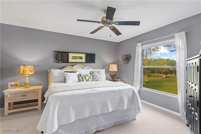 bedroom with carpet floors, a ceiling fan, baseboards, and a textured ceiling