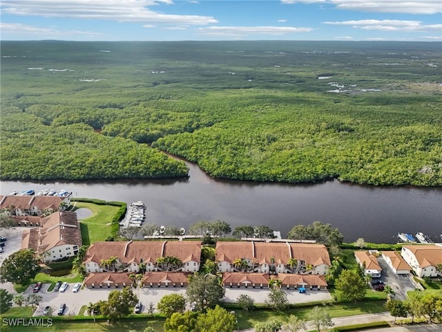 drone / aerial view featuring a water view, a wooded view, and a residential view