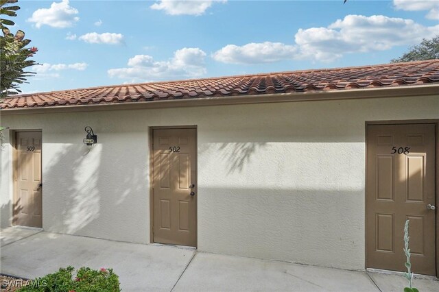 entrance to property featuring a tiled roof and stucco siding