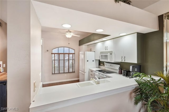 kitchen featuring ceiling fan, sink, kitchen peninsula, white appliances, and white cabinets