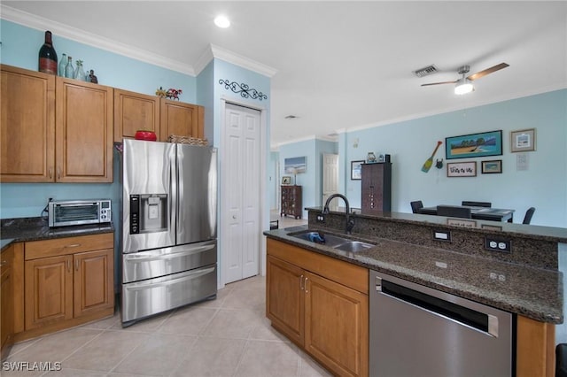 kitchen featuring ceiling fan, sink, stainless steel appliances, dark stone counters, and ornamental molding