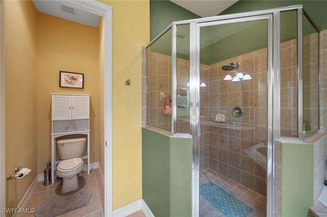 bathroom featuring tile patterned flooring, toilet, and a shower with door