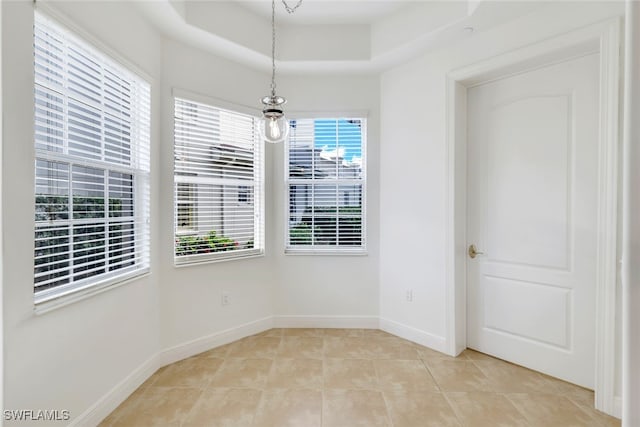 tiled empty room with a raised ceiling