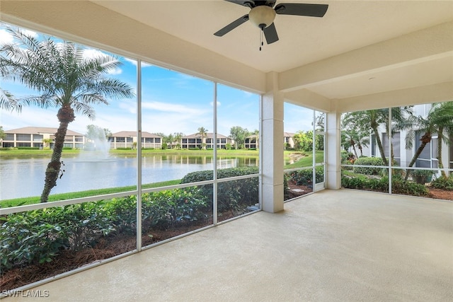 unfurnished sunroom featuring ceiling fan and a water view