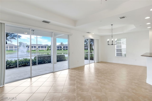 spare room with a notable chandelier, a raised ceiling, and light tile patterned floors