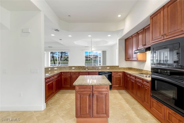 kitchen with light stone countertops, a center island, kitchen peninsula, a tray ceiling, and black appliances