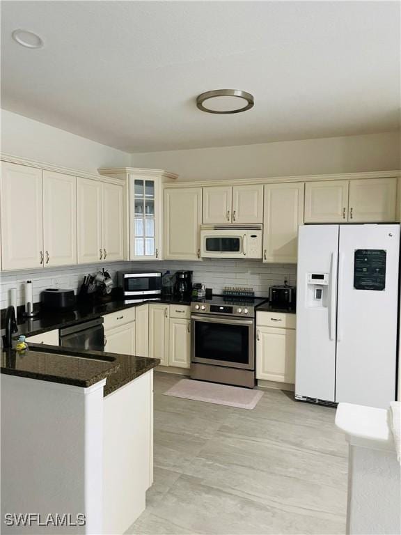 kitchen featuring kitchen peninsula, stainless steel appliances, cream cabinetry, and tasteful backsplash