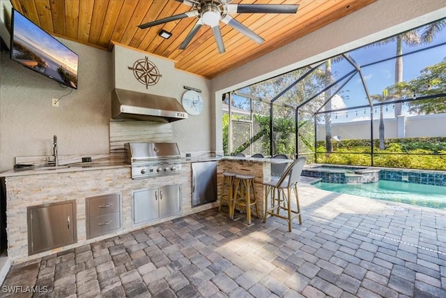 view of patio featuring an outdoor kitchen, a lanai, ceiling fan, an outdoor wet bar, and grilling area