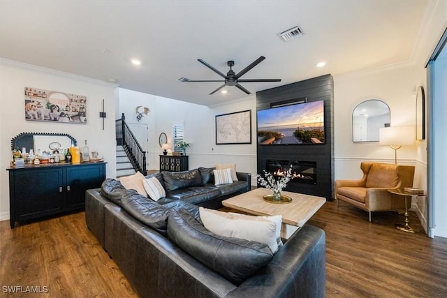 living room featuring a large fireplace, dark hardwood / wood-style floors, ceiling fan, and crown molding