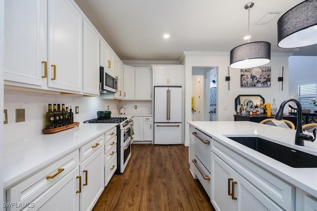 kitchen with high end appliances, white cabinets, sink, dark hardwood / wood-style floors, and decorative light fixtures