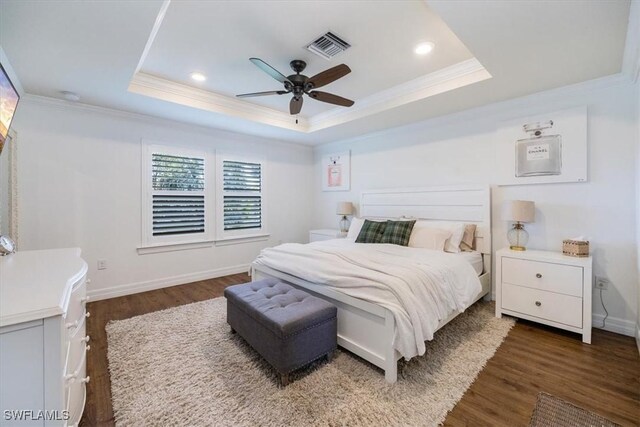 bedroom with ceiling fan, crown molding, dark wood-type flooring, and a tray ceiling