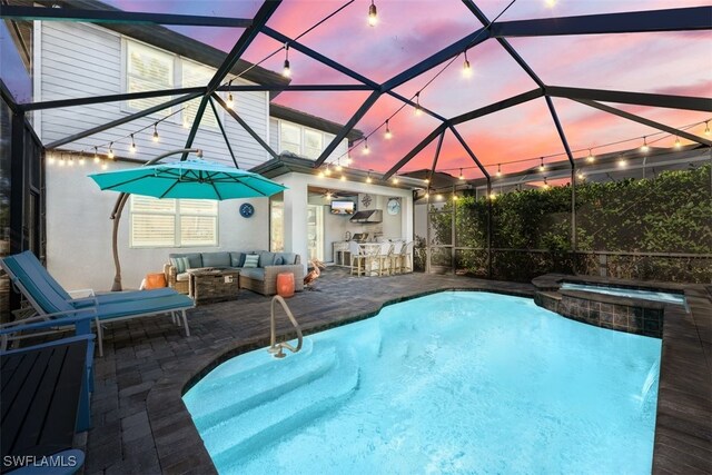 pool at dusk featuring outdoor lounge area, a lanai, an outdoor bar, a patio area, and an in ground hot tub