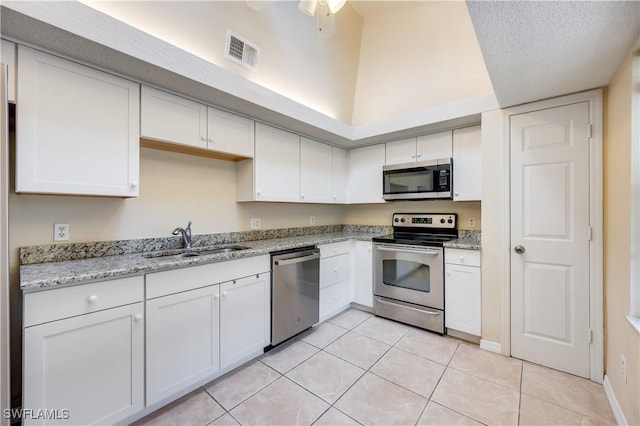 kitchen featuring white cabinetry, sink, light tile patterned floors, and appliances with stainless steel finishes