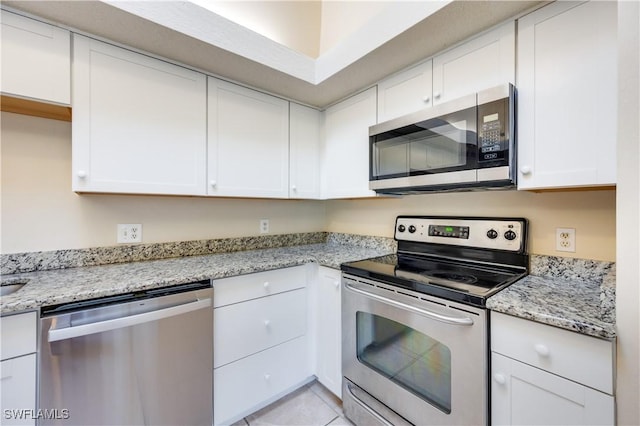 kitchen with white cabinetry, light tile patterned floors, light stone counters, and appliances with stainless steel finishes