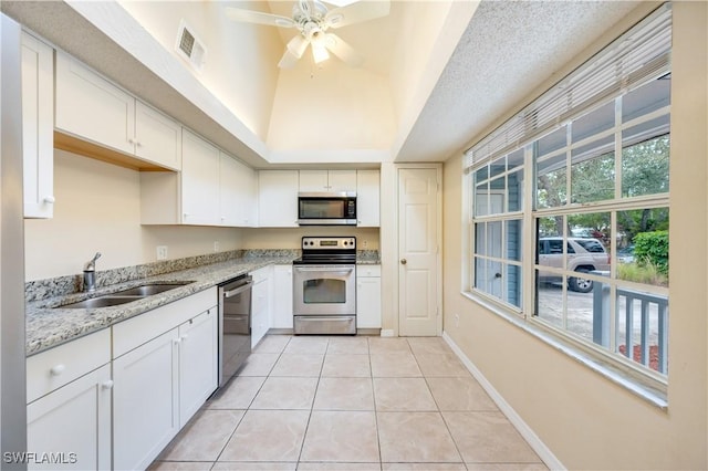 kitchen with appliances with stainless steel finishes, light tile patterned floors, white cabinetry, and sink