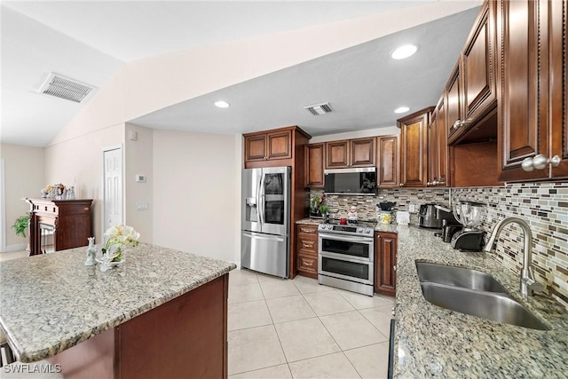 kitchen with light stone countertops, sink, backsplash, lofted ceiling, and appliances with stainless steel finishes