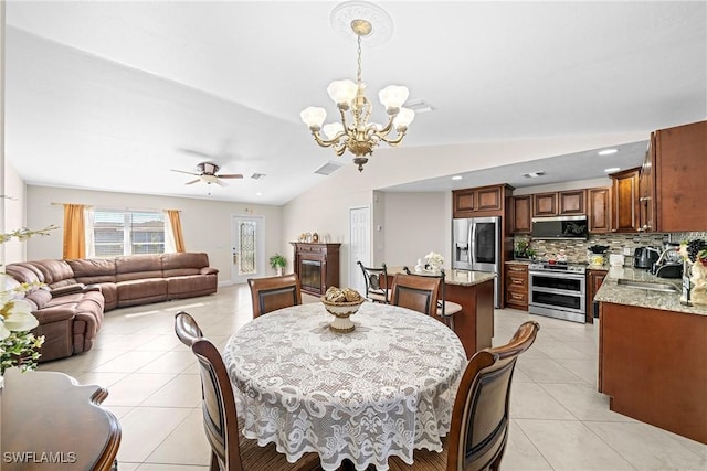 dining area with light tile patterned floors, ceiling fan with notable chandelier, lofted ceiling, and sink