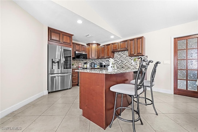 kitchen with backsplash, vaulted ceiling, light tile patterned floors, light stone counters, and stainless steel appliances