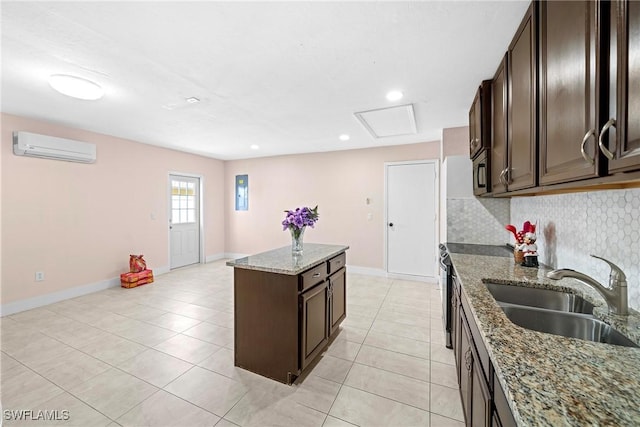 kitchen with a wall mounted air conditioner, decorative backsplash, sink, stone counters, and a center island