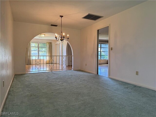 empty room featuring carpet flooring and a notable chandelier