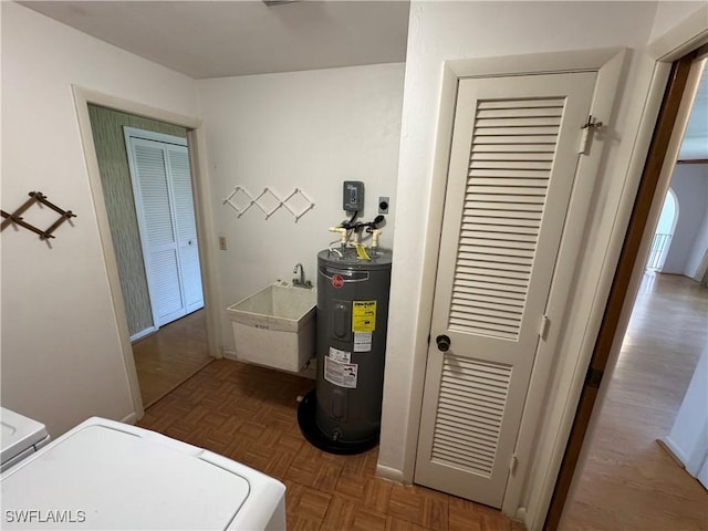 utility room featuring sink, washing machine and dryer, and water heater