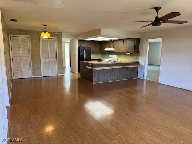 kitchen featuring stainless steel fridge with ice dispenser, dark wood-type flooring, kitchen peninsula, and white range with electric stovetop