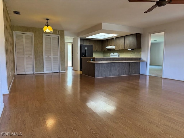 kitchen featuring stainless steel refrigerator with ice dispenser, dark brown cabinets, light hardwood / wood-style flooring, kitchen peninsula, and ceiling fan