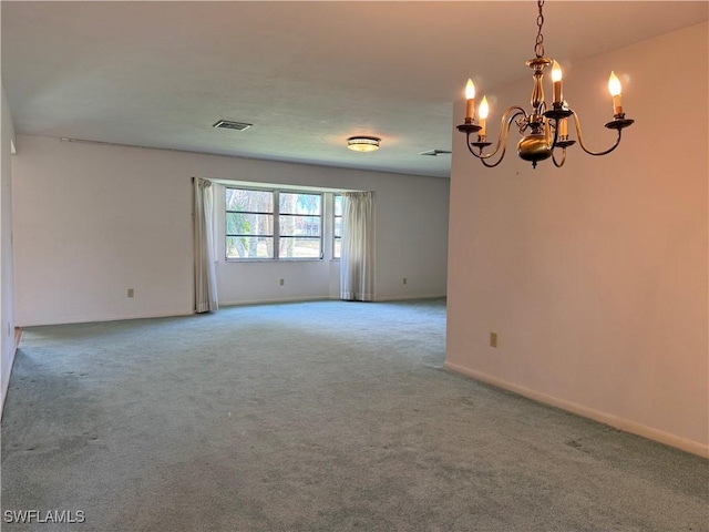 carpeted spare room featuring a notable chandelier