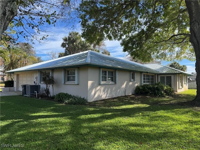 view of side of home featuring a garage, a lawn, and central AC