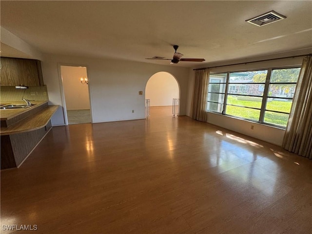 unfurnished living room with ceiling fan, sink, and light wood-type flooring