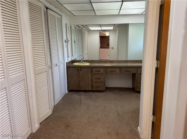 hall featuring sink, a paneled ceiling, and dark carpet