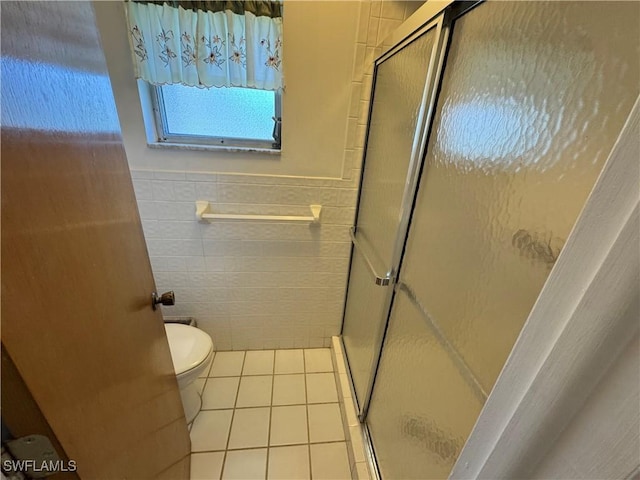 bathroom featuring toilet, tile walls, tile patterned floors, and a shower with shower door