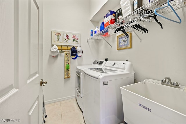 clothes washing area with sink, light tile patterned floors, and independent washer and dryer