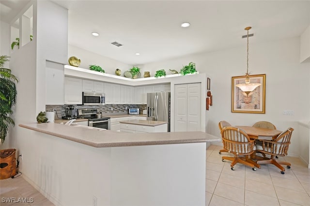 kitchen with stainless steel appliances, tasteful backsplash, kitchen peninsula, pendant lighting, and light tile patterned floors