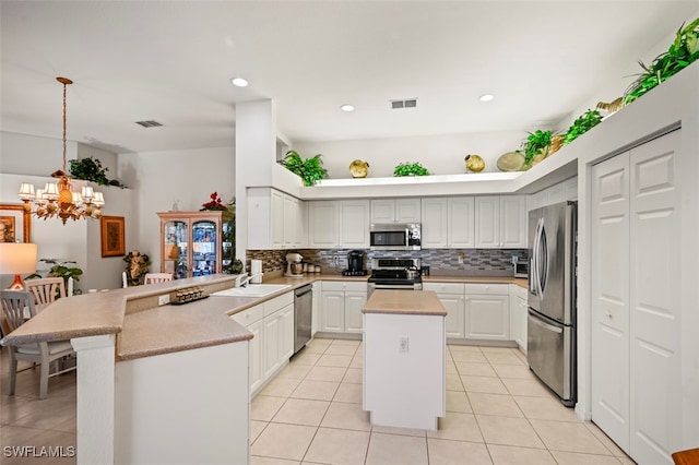 kitchen with appliances with stainless steel finishes, decorative light fixtures, a kitchen island, kitchen peninsula, and a chandelier