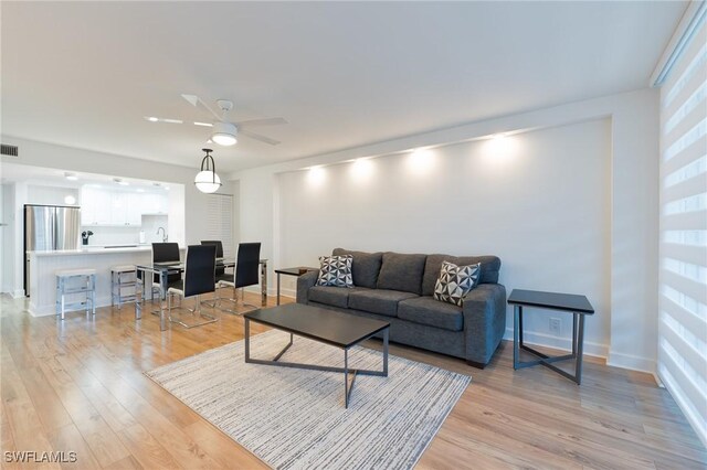 living room with ceiling fan and light hardwood / wood-style flooring