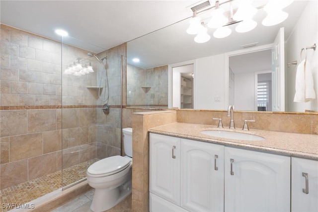 bathroom featuring a tile shower, tile patterned floors, vanity, and toilet