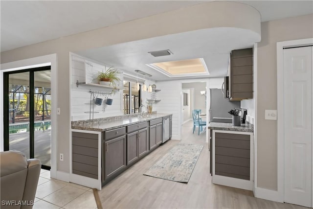 kitchen featuring pendant lighting, sink, appliances with stainless steel finishes, dark brown cabinets, and light stone counters