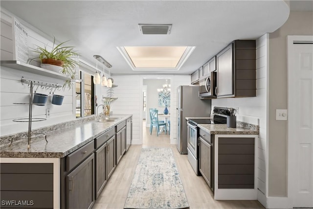 kitchen featuring dark brown cabinetry, sink, stainless steel appliances, an inviting chandelier, and decorative light fixtures