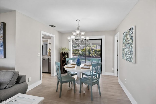 dining space with light wood-type flooring and an inviting chandelier