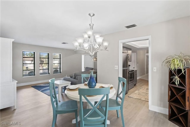 dining area with light hardwood / wood-style floors and an inviting chandelier