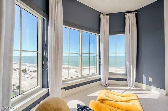 interior space with plenty of natural light, a view of the beach, and a water view